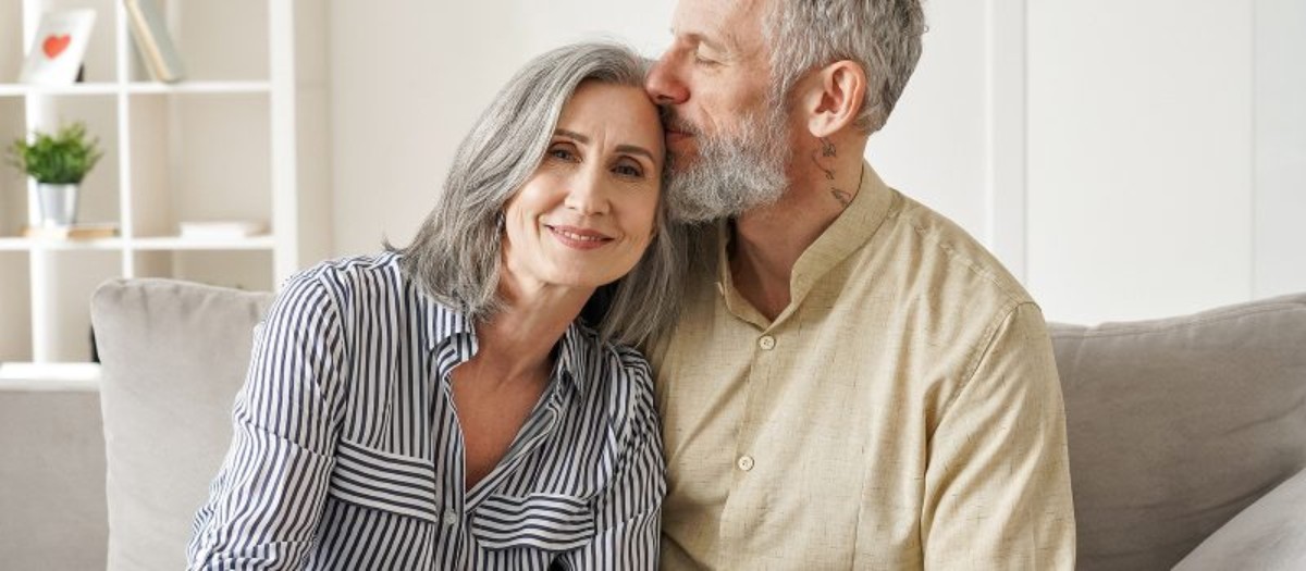 Un couple âgé heureux, assis sur un canapé, symbolisant 60 ans d’amour et de complicité lors de leurs noces de diamant.